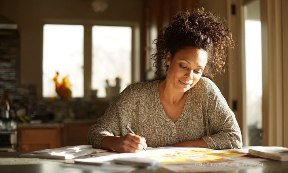 Homeowner filling out rebate paperwork at a table with sunlight shining through new energy-efficient windows